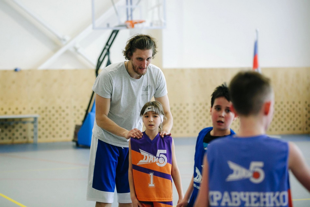 Играющий тренер показывает технику детям на тренировке